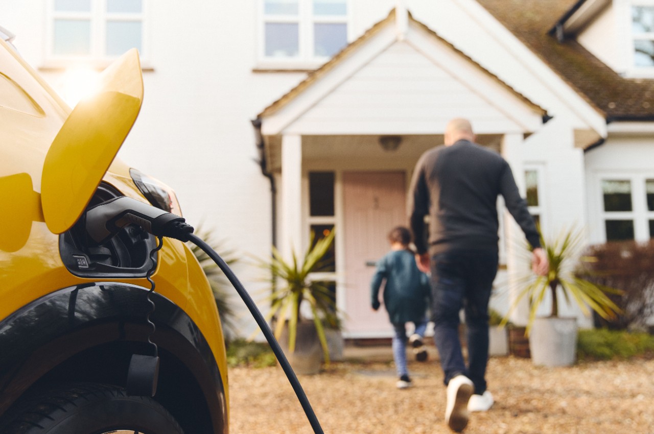 EV car foreground Dad and Son entering home